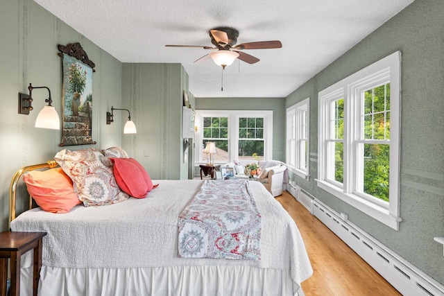 730 3rd St S, Wisconsin Rapids, WI 54494 - bedroom featuring a baseboard heating unit, wood finished floors, a textured ceiling, and a ceiling fan