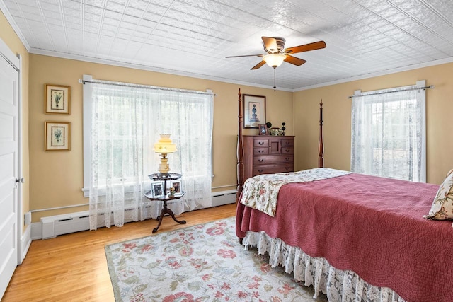 730 3rd St S, Wisconsin Rapids, WI 54494 - bedroom featuring multiple windows, crown molding, wood finished floors, a baseboard heating unit, and a ceiling fan