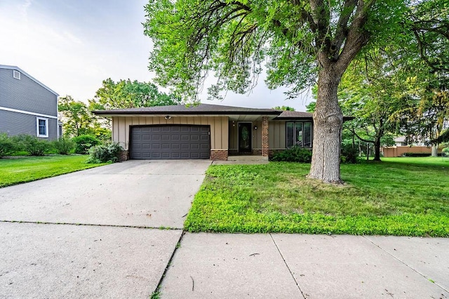 1311 Hickory St, Onalaska, WI 54650 - view of front of house with board and batten siding, a garage, driveway, a front lawn, and brick siding