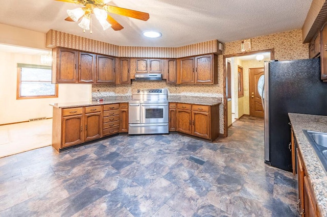 1311 Hickory St, Onalaska, WI 54650 - kitchen with appliances with stainless steel finishes, under cabinet range hood, brown cabinetry, ceiling fan, and light countertops