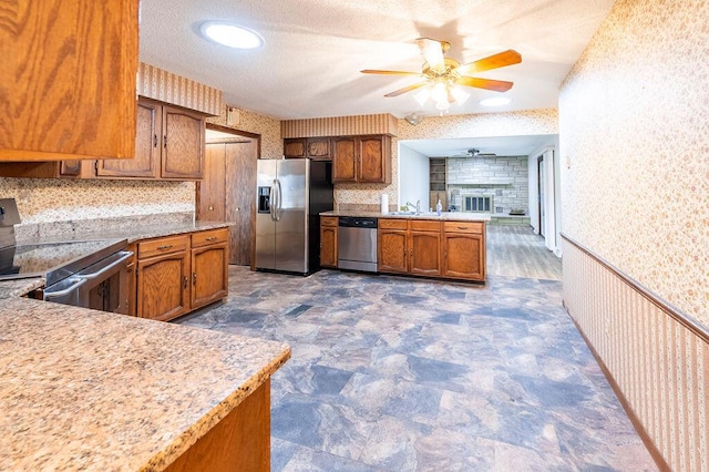 1311 Hickory St, Onalaska, WI 54650 - kitchen featuring appliances with stainless steel finishes, ceiling fan, wallpapered walls, a peninsula, and light countertops