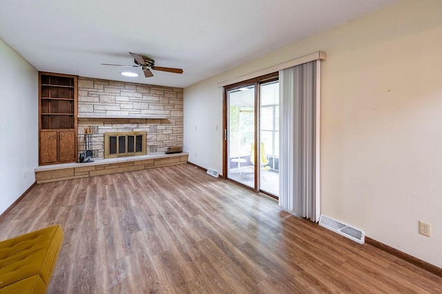 1311 Hickory St, Onalaska, WI 54650 - unfurnished living room with a ceiling fan, wood finished floors, a stone fireplace, and built in shelves