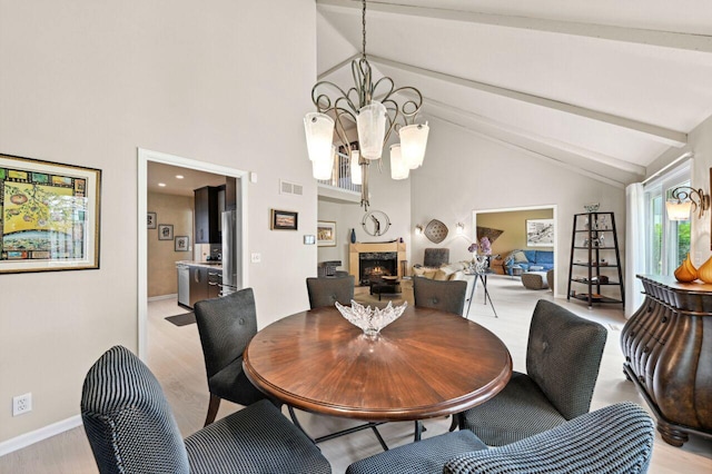 9125 N Briarwood Ct, Bayside, WI 53217 - dining space featuring beam ceiling, a chandelier, a lit fireplace, high vaulted ceiling, and light wood-style floors