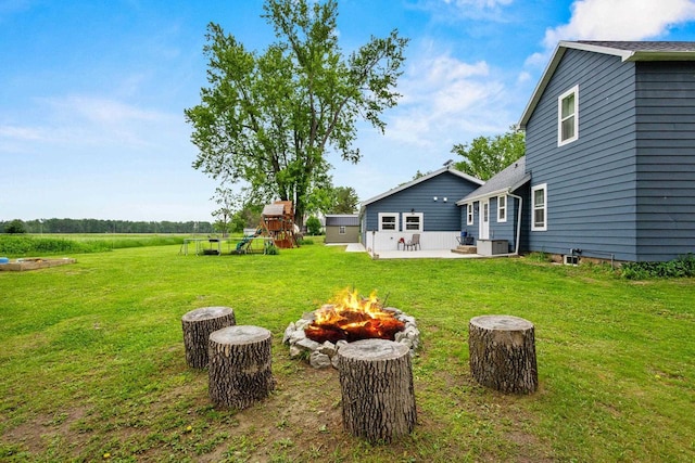 N6965 Thede Rd, Black Creek, WI 54106 - view of grassy yard featuring an outdoor fire pit, a patio area, and a playground