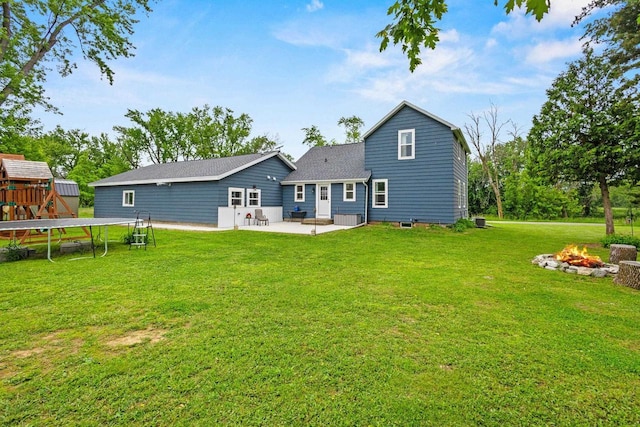 N6965 Thede Rd, Black Creek, WI 54106 - rear view of house with a trampoline, a patio area, an outdoor fire pit, a lawn, and a shingled roof