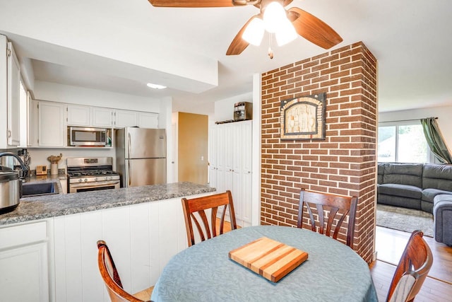 2743 Bluebird Ln, Cottage Grove, WI 53527 - kitchen featuring stainless steel appliances, a peninsula, white cabinetry, a ceiling fan, and wood finished floors
