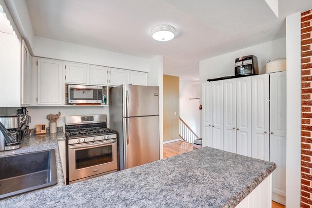 2743 Bluebird Ln, Cottage Grove, WI 53527 - kitchen with stainless steel appliances, white cabinets, and light wood-style flooring