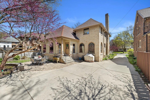 4765 N Woodburn St, Whitefish Bay, WI 53211 - rear view of property featuring brick siding, a chimney, a patio area, and a shingled roof