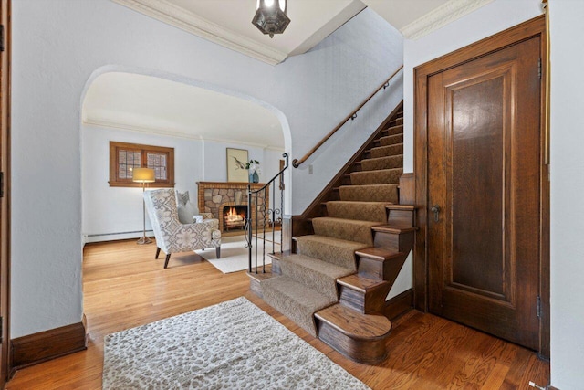 4765 N Woodburn St, Whitefish Bay, WI 53211 - entrance foyer with arched walkways, ornamental molding, a stone fireplace, stairs, and wood finished floors