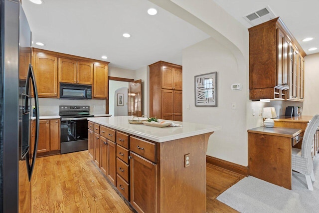 4765 N Woodburn St, Whitefish Bay, WI 53211 - kitchen with black appliances, arched walkways, light wood-type flooring, a center island, and recessed lighting