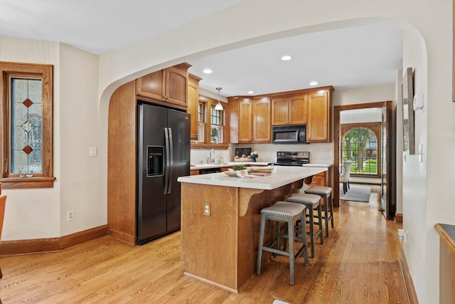 4765 N Woodburn St, Whitefish Bay, WI 53211 - kitchen with refrigerator with ice dispenser, black microwave, arched walkways, light wood-style flooring, and recessed lighting