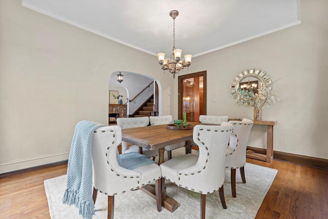 4765 N Woodburn St, Whitefish Bay, WI 53211 - dining space featuring arched walkways, a chandelier, crown molding, light wood finished floors, and stairway