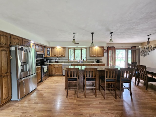 200890 Robin Rd, Marshfield, WI 54449 - kitchen with appliances with stainless steel finishes, light wood-type flooring, a breakfast bar area, a chandelier, and a kitchen island