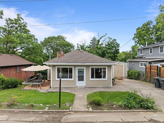 N1808 Woodland Rd, Lake Geneva, WI 53147 - view of front of house featuring a patio area, a chimney, a storage shed, and roof with shingles