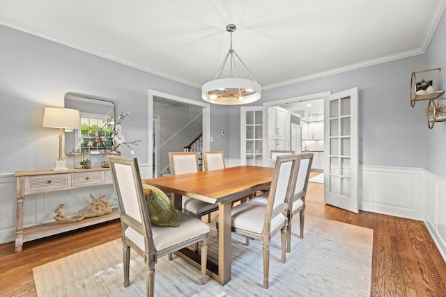 6123 N Berkeley Blvd, Whitefish Bay, WI 53217 - dining area with wood finished floors, a chandelier, a wainscoted wall, ornamental molding, and stairs