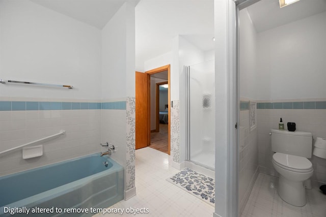 452 Woodland Dr, Wisconsin Rapids, WI 54494 - bathroom featuring tile walls, a bath, a wainscoted wall, and a stall shower