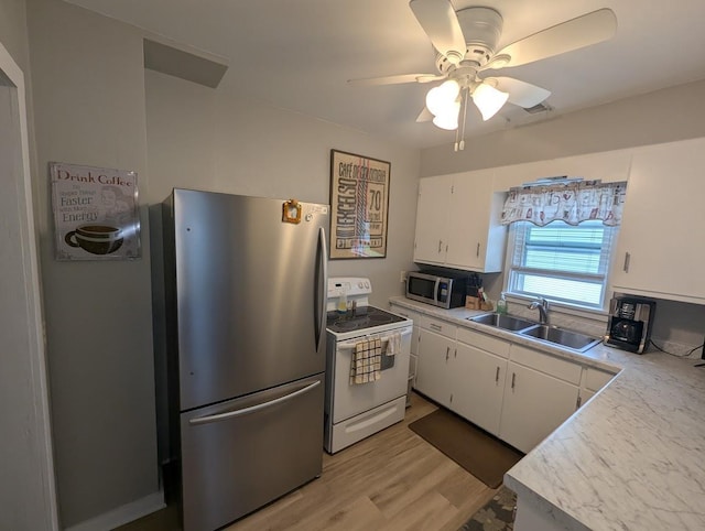 219 Guenther St, Oshkosh, WI 54902 - kitchen with stainless steel appliances, white cabinets, light countertops, a ceiling fan, and light wood-style floors