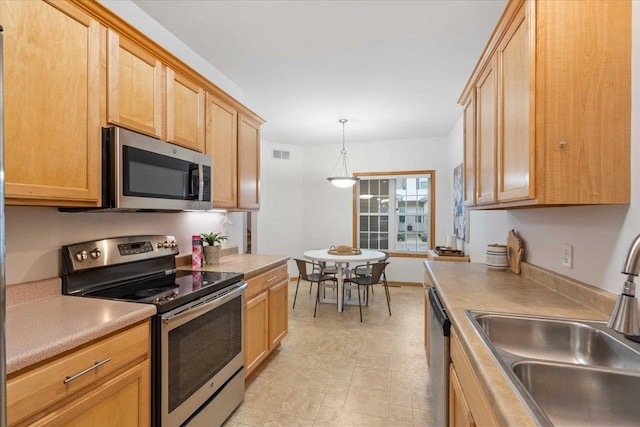 3869 Maple Grove Dr, Madison, WI 53719 - kitchen with stainless steel appliances, light brown cabinets, light countertops, and hanging light fixtures