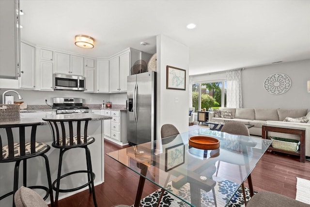 150 E Fairmount Ave, Whitefish Bay, WI 53217 - kitchen featuring appliances with stainless steel finishes, a peninsula, open floor plan, a kitchen bar, and white cabinetry
