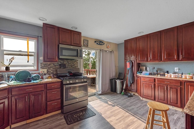N7082 Airport Rd, Beaver Dam, WI 53916 - kitchen featuring appliances with stainless steel finishes, reddish brown cabinets, decorative backsplash, and light wood-style flooring