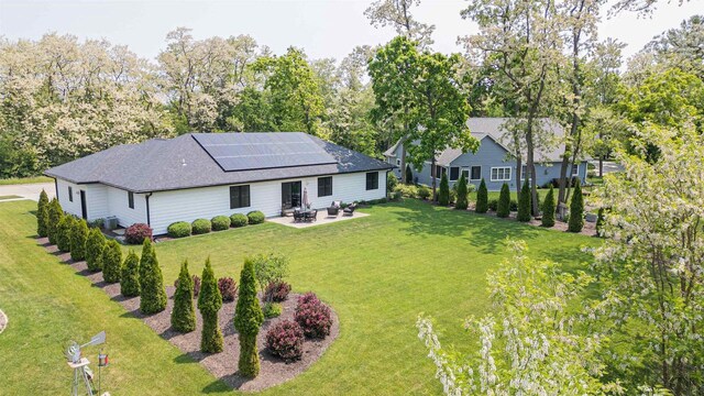 3717 White Pine Dr, Janesville, WI 53545 - back of property with a patio area, roof mounted solar panels, a lawn, a fire pit, and view of wooded area