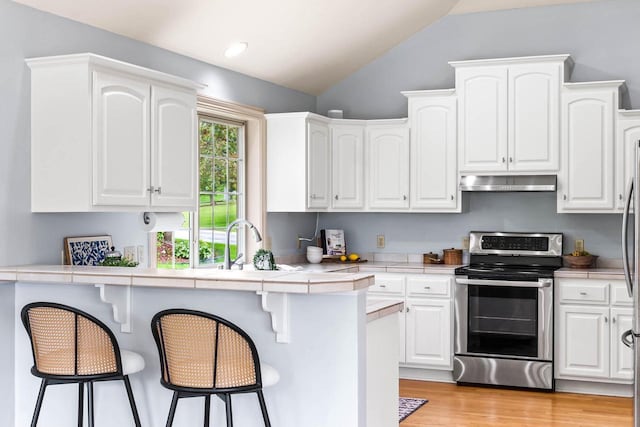 N53W16527 Whitetail Run, Menomonee Falls, WI 53051 - kitchen featuring stainless steel electric range, under cabinet range hood, tile countertops, a kitchen bar, and lofted ceiling