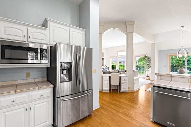 N53W16527 Whitetail Run, Menomonee Falls, WI 53051 - kitchen with stainless steel appliances, tile counters, white cabinets, light wood-style flooring, and ornate columns
