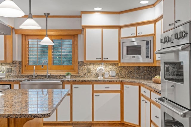 13835 Stonefield Ct, Elm Grove, WI 53122 - kitchen with stainless steel microwave, white cabinetry, tasteful backsplash, hanging light fixtures, and light stone countertops