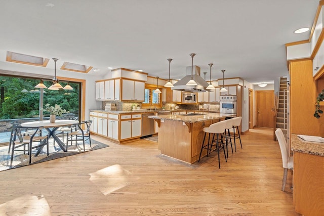 13835 Stonefield Ct, Elm Grove, WI 53122 - kitchen featuring stainless steel appliances, a kitchen breakfast bar, tasteful backsplash, light stone countertops, and recessed lighting