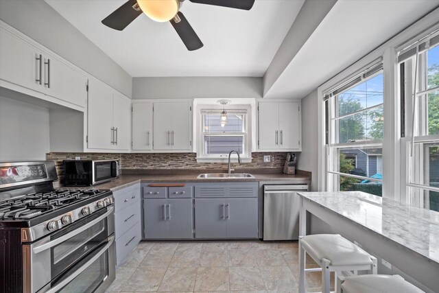 165 N 72nd St, Milwaukee, WI 53213 - kitchen with appliances with stainless steel finishes, tasteful backsplash, gray cabinets, dark countertops, and white cabinetry