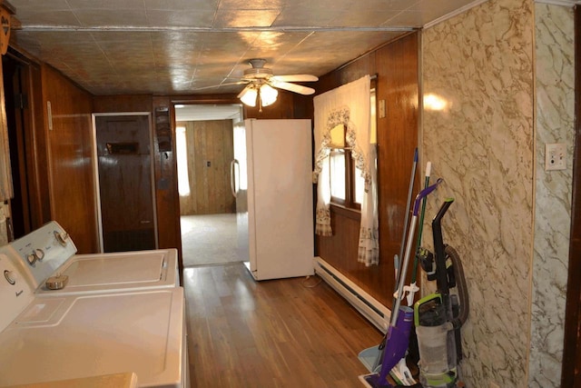 653 Grant St, Wonewoc, WI 53968 - laundry room featuring a baseboard heating unit, independent washer and dryer, wood finished floors, a ceiling fan, and wooden walls