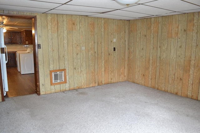 653 Grant St, Wonewoc, WI 53968 - spare room featuring washer / dryer, carpet flooring, wood walls, heating unit, and a paneled ceiling