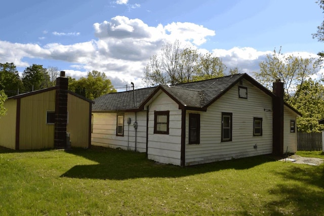 653 Grant St, Wonewoc, WI 53968 - view of property exterior featuring a chimney, a lawn, roof with shingles, and an outbuilding