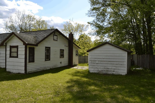 653 Grant St, Wonewoc, WI 53968 - rear view of property with a chimney, roof with shingles, and a storage shed