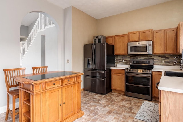 850 E Mckearn Ln, Beloit, WI 53511 - kitchen with appliances with stainless steel finishes, decorative backsplash, arched walkways, and light countertops