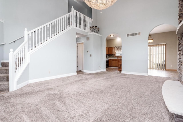 850 E Mckearn Ln, Beloit, WI 53511 - unfurnished living room with arched walkways, a towering ceiling, carpet, stairway, and a chandelier
