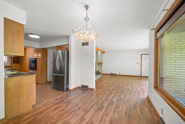 5110 W Cleveland Ave, Milwaukee, WI 53219 - kitchen with freestanding refrigerator, black oven, wood finished floors, a chandelier, and open floor plan