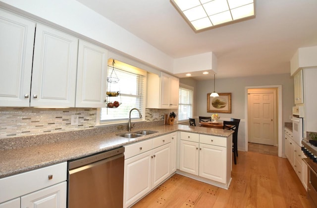 4729 James Ave, Wind Point, WI 53402 - kitchen featuring stainless steel dishwasher, a peninsula, white oven, decorative backsplash, and white cabinets