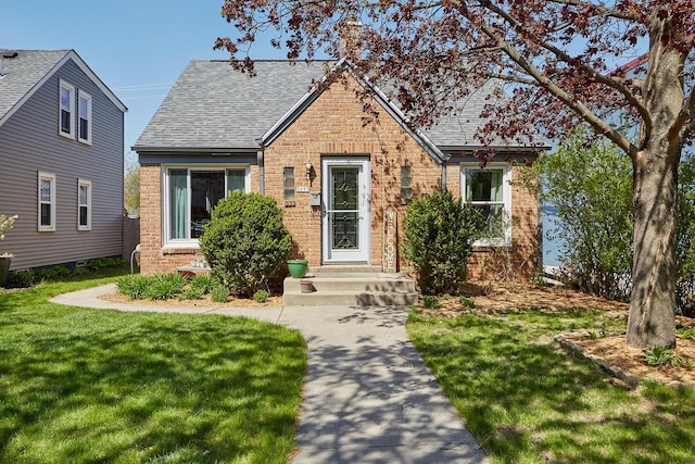3057 N 90th St, Milwaukee, WI 53222 - tudor home with brick siding, roof with shingles, a front yard, and a chimney
