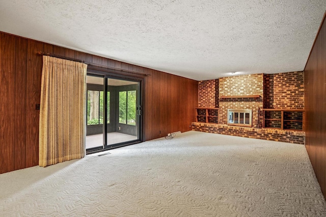 5325 Linden Cir, Racine, WI 53406 - unfurnished living room featuring wood walls, carpet, a textured ceiling, and a brick fireplace