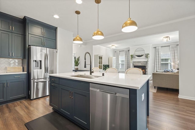 7949 W Oakwood Way, Franklin, WI 53132 - kitchen with appliances with stainless steel finishes, open floor plan, light countertops, a warm lit fireplace, and tasteful backsplash