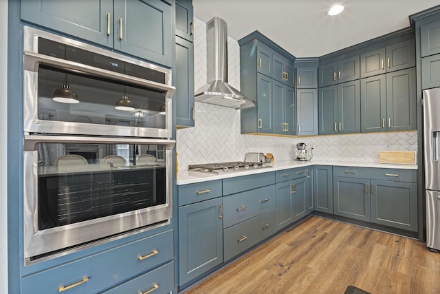 7949 W Oakwood Way, Franklin, WI 53132 - kitchen with appliances with stainless steel finishes, wall chimney range hood, decorative backsplash, and light wood-style floors