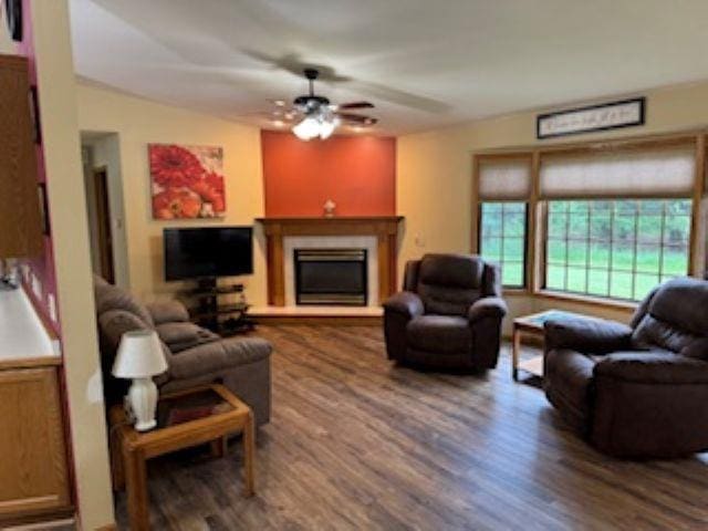 1064 Sunny Ridge Cir, Nekoosa, WI 54457 - living area with wood finished floors, a fireplace with raised hearth, and a ceiling fan