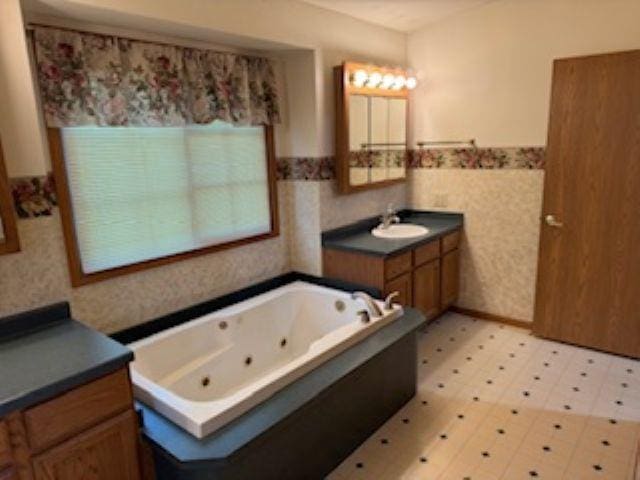 1064 Sunny Ridge Cir, Nekoosa, WI 54457 - bathroom featuring vanity, wainscoting, a whirlpool tub, tile patterned floors, and tile walls