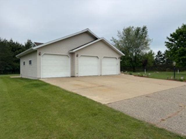 1064 Sunny Ridge Cir, Nekoosa, WI 54457 - view of side of property with an attached garage, a lawn, and driveway