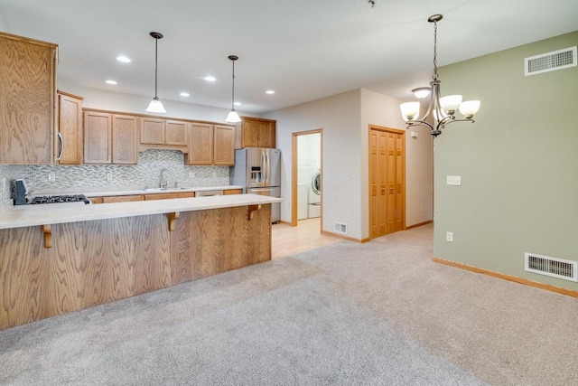7942 Williamsburg Ct Unit 101, Bristol, WI 53104 - kitchen featuring stainless steel refrigerator with ice dispenser, light countertops, a peninsula, washer / dryer, and decorative backsplash