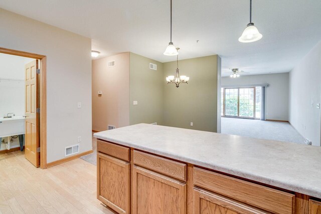 7942 Williamsburg Ct Unit 101, Bristol, WI 53104 - kitchen featuring ceiling fan, pendant lighting, light wood-style floors, and light countertops