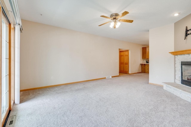 7942 Williamsburg Ct Unit 101, Bristol, WI 53104 - unfurnished living room featuring light carpet, a fireplace, a ceiling fan, and healthy amount of natural light