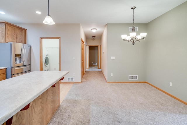 7942 Williamsburg Ct Unit 101, Bristol, WI 53104 - kitchen featuring stainless steel refrigerator with ice dispenser, washer / clothes dryer, hanging light fixtures, light countertops, and a chandelier