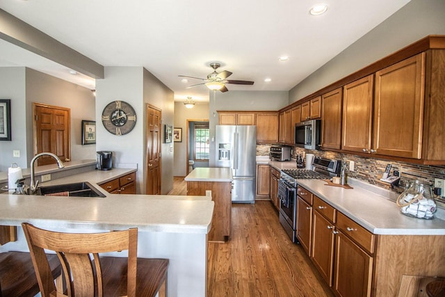 120 Wind Sail Ct, Random Lake, WI 53075 - kitchen featuring stainless steel appliances, a kitchen island, wood finished floors, brown cabinets, and recessed lighting